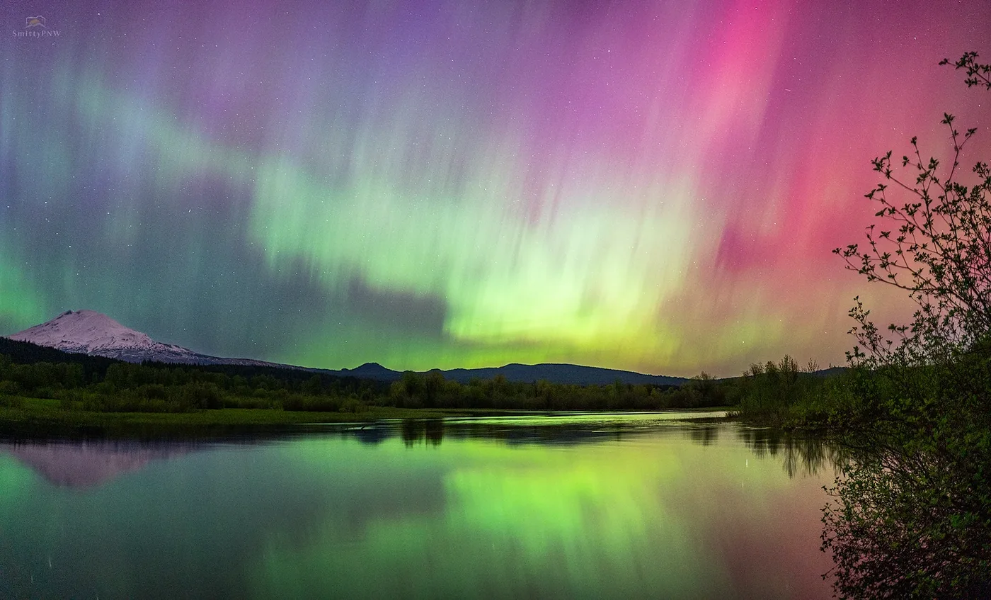 Mount Adams beneath vivid pink and green aurora reflected in Pacific Northwest water